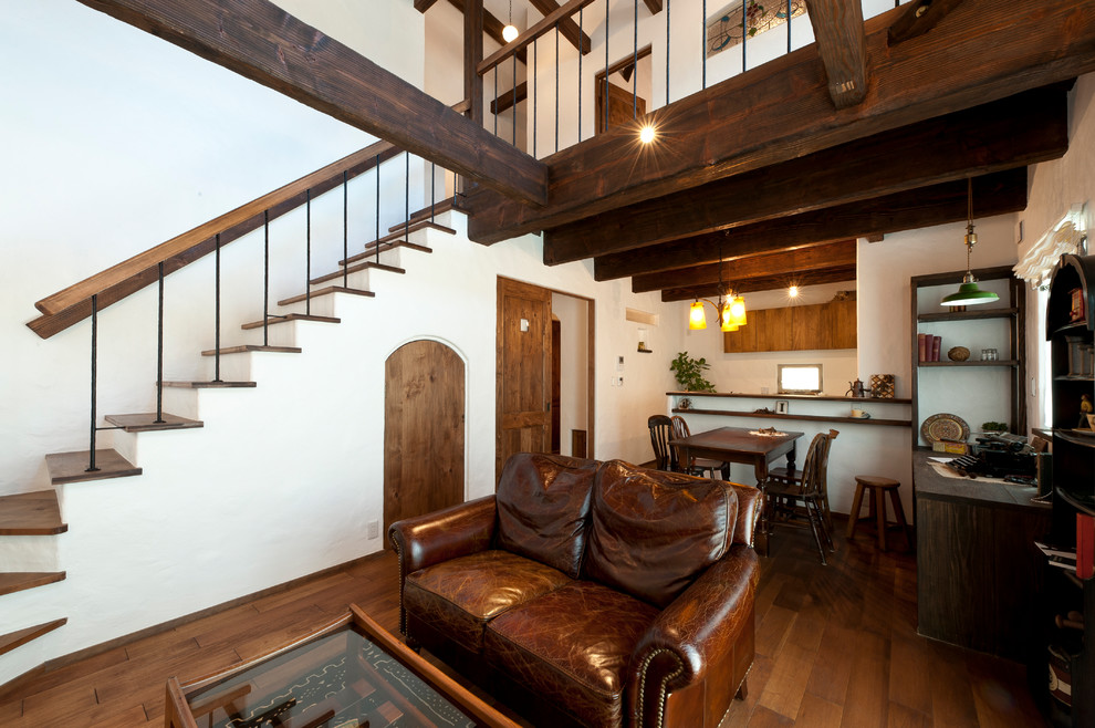 Ejemplo de salón abierto mediterráneo pequeño sin chimenea con paredes blancas, suelo de madera oscura, televisor colgado en la pared y suelo marrón
