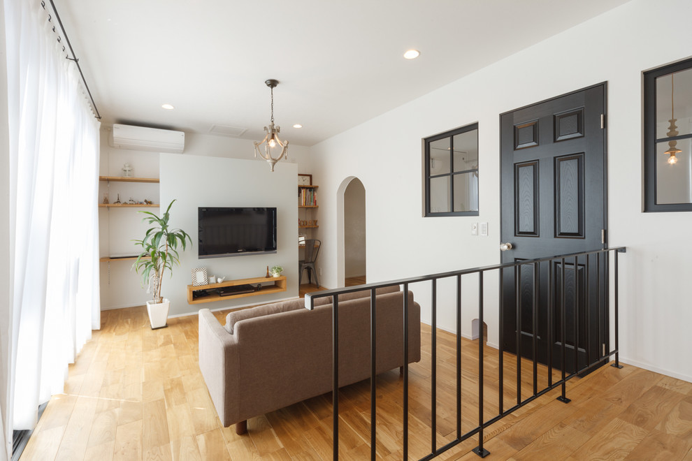 Offenes Klassisches Wohnzimmer mit weißer Wandfarbe, braunem Holzboden, freistehendem TV und braunem Boden in Sonstige