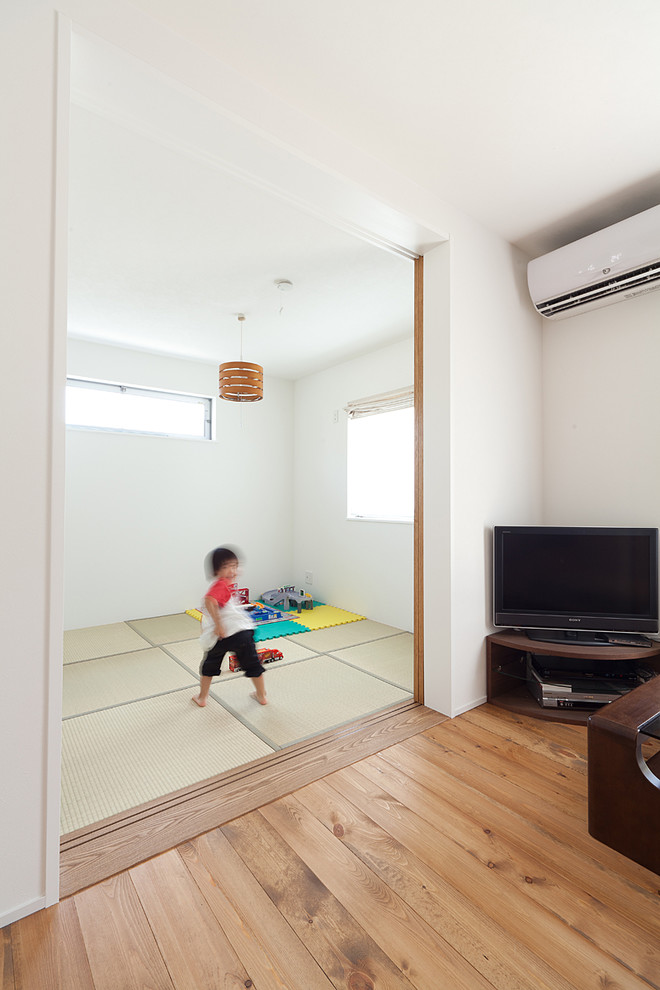 Идея дизайна: гостиная комната с белыми стенами, татами, отдельно стоящим телевизором и зеленым полом
