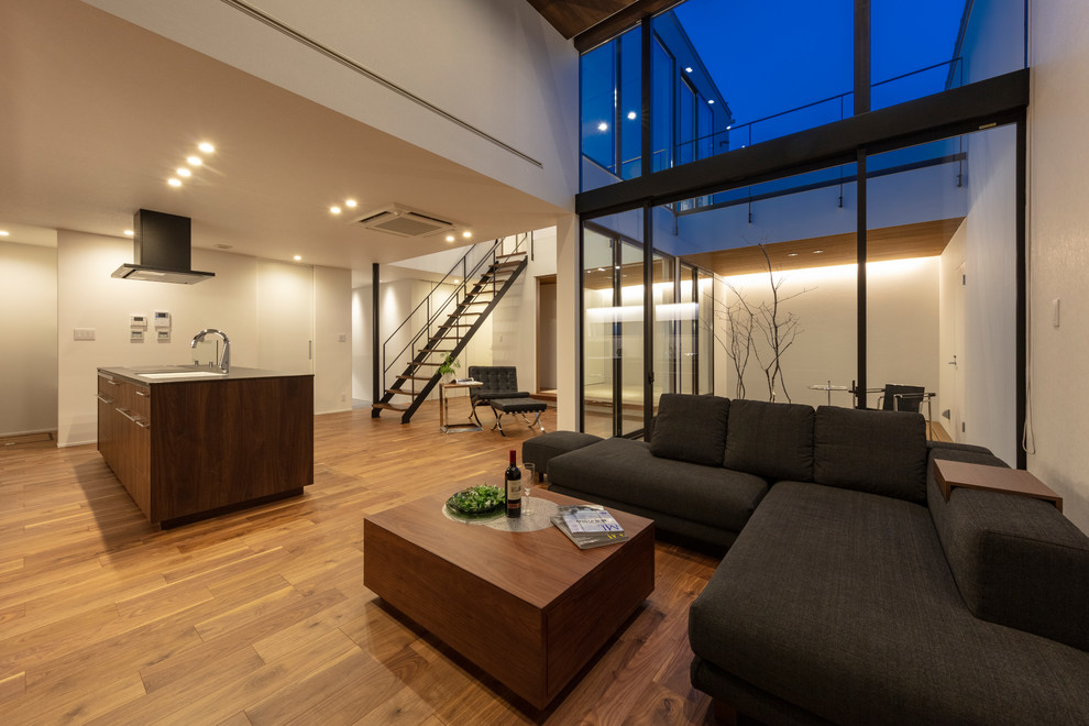 Cette image montre un grand salon minimaliste ouvert avec un mur blanc, un sol marron, parquet foncé, un plafond en bois et du lambris.
