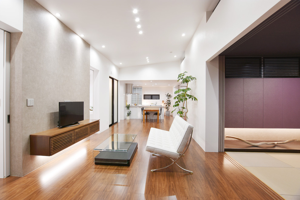 Свежая идея для дизайна: открытая гостиная комната в стиле модернизм с серыми стенами, полом из фанеры и коричневым полом без камина - отличное фото интерьера