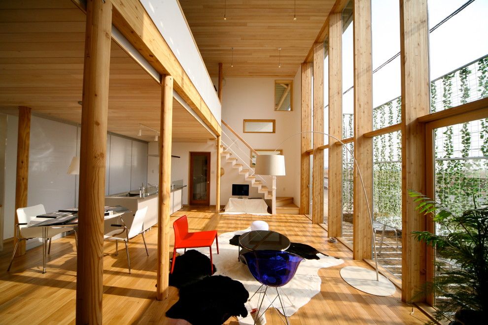 Modelo de salón abierto asiático de tamaño medio con paredes blancas, suelo de madera en tonos medios, televisor independiente y suelo beige