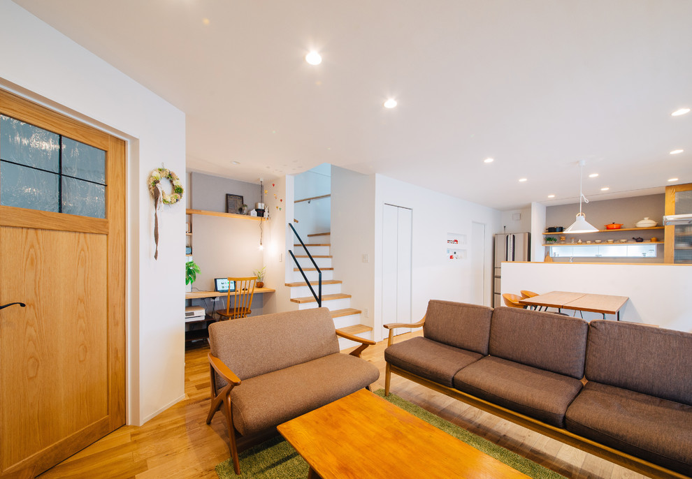 Offenes Skandinavisches Wohnzimmer mit weißer Wandfarbe, braunem Holzboden und braunem Boden in Sonstige