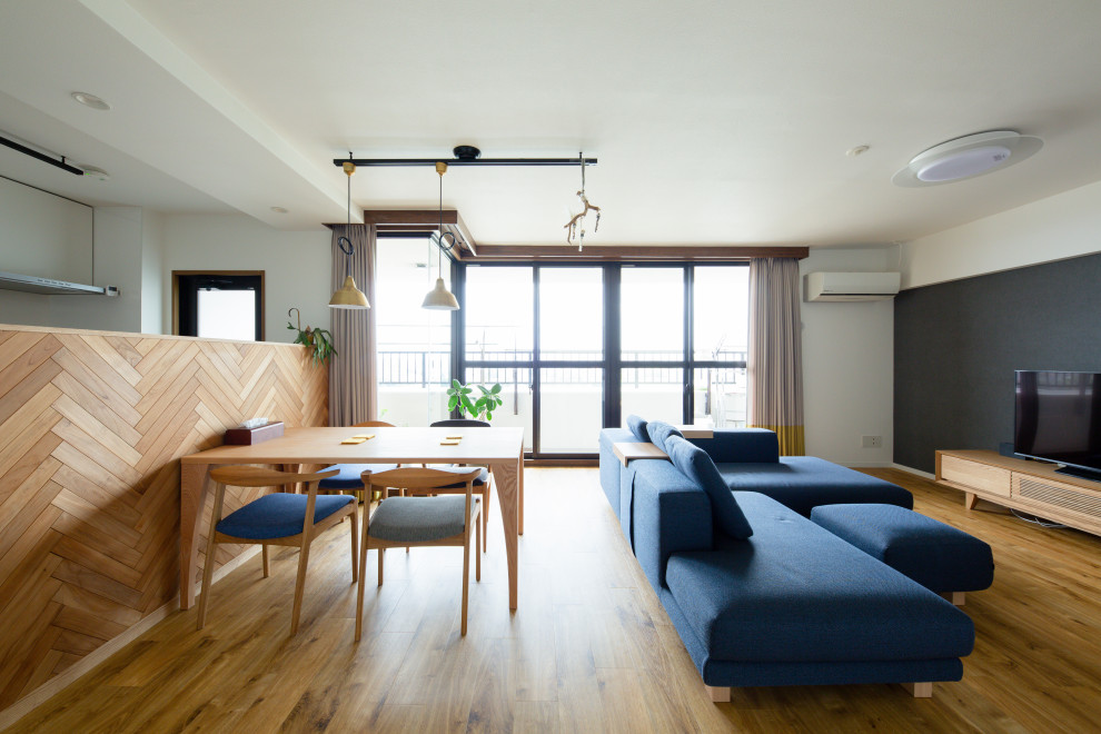 World-inspired open plan living room in Nagoya with blue walls and a freestanding tv.