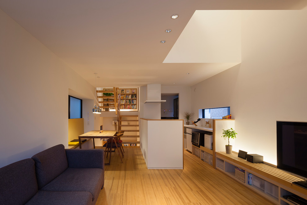Exempel på ett asiatiskt allrum med öppen planlösning, med en fristående TV, vita väggar och mellanmörkt trägolv