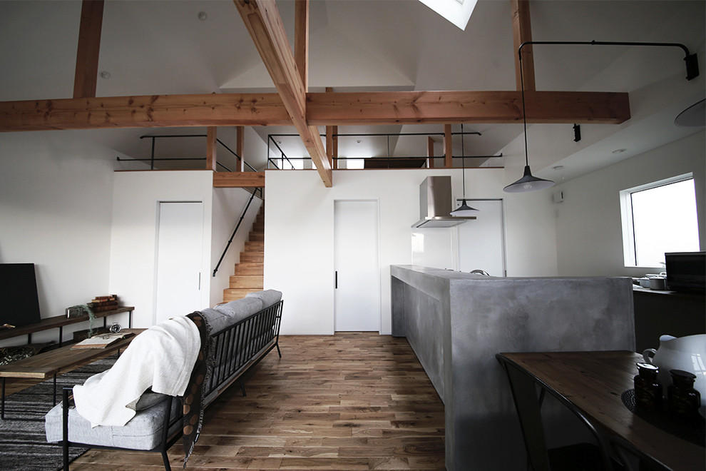 Foto di un soggiorno industriale aperto con pareti bianche, pavimento in legno massello medio, TV autoportante e pavimento marrone