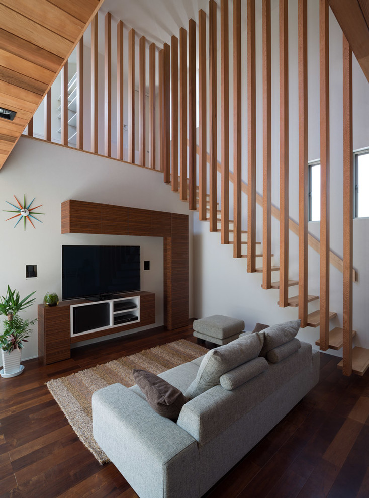 Modernes Wohnzimmer mit weißer Wandfarbe, freistehendem TV, dunklem Holzboden und braunem Boden in Fukuoka