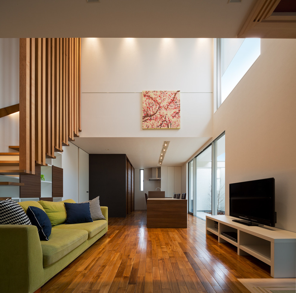 Источник вдохновения для домашнего уюта: открытая гостиная комната в стиле модернизм с белыми стенами, паркетным полом среднего тона, отдельно стоящим телевизором и коричневым полом