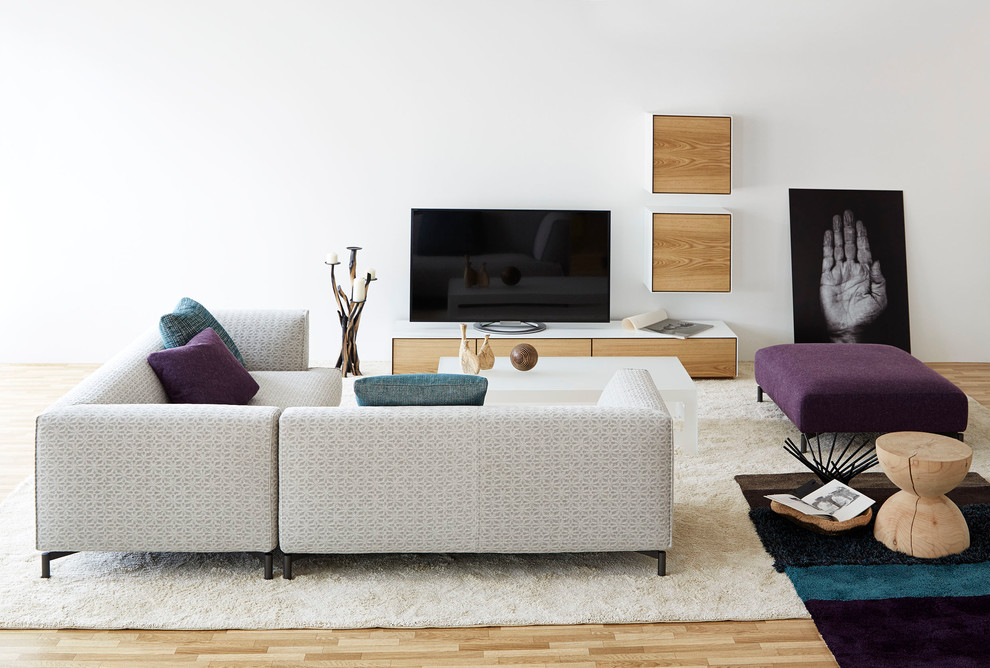 Immagine di un soggiorno moderno con pareti bianche, parquet chiaro e TV autoportante