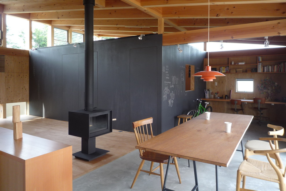Idées déco pour un petit salon asiatique ouvert avec un mur noir, sol en béton ciré, un poêle à bois et un manteau de cheminée en bois.