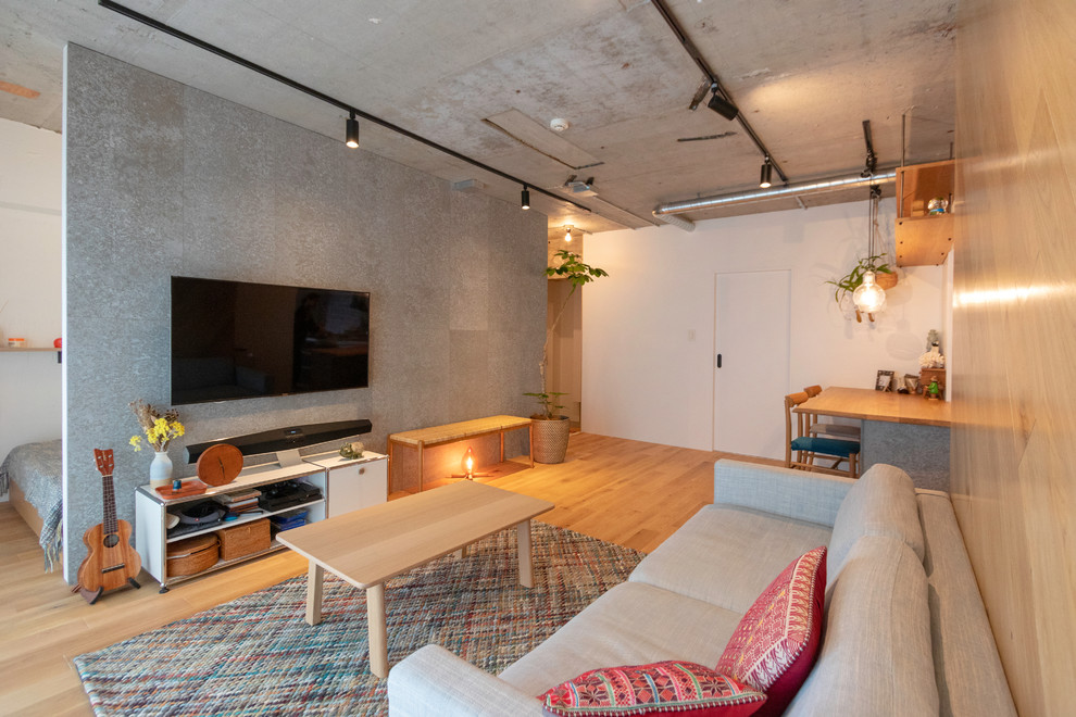 This is an example of an urban living room in Tokyo with white walls, light hardwood flooring, a wall mounted tv and beige floors.