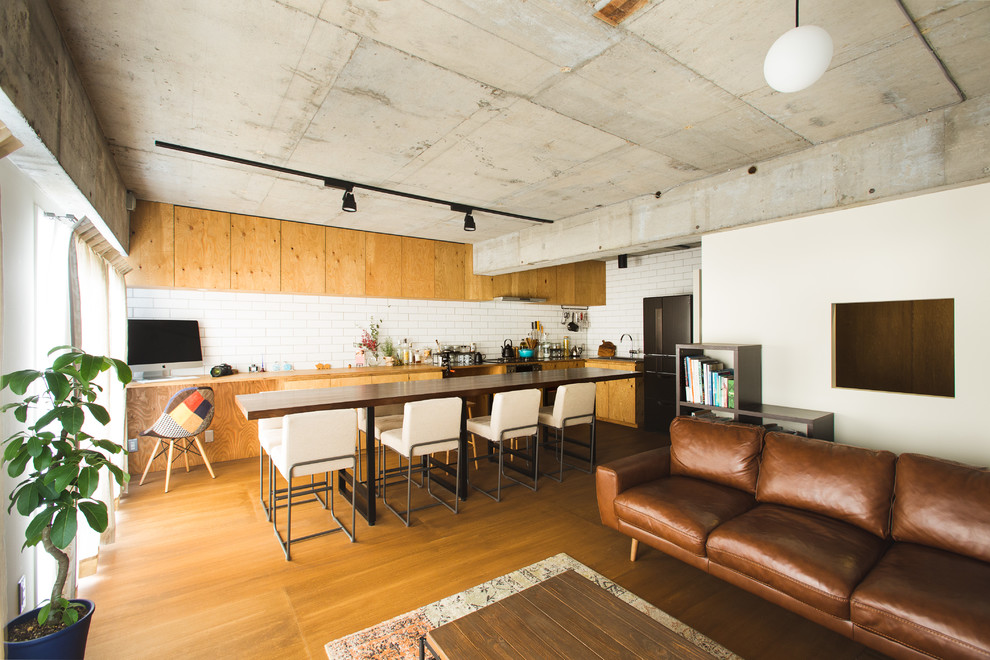 Aménagement d'un salon industriel ouvert avec un mur blanc et un sol en bois brun.