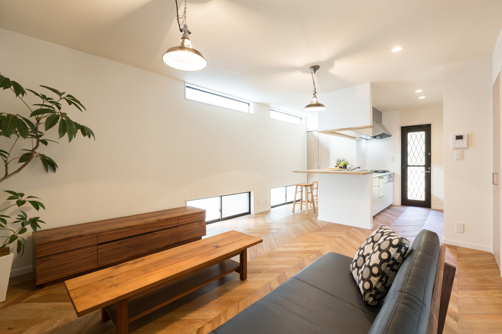 Fernseherloses, Offenes Modernes Wohnzimmer ohne Kamin mit weißer Wandfarbe und braunem Holzboden in Sonstige