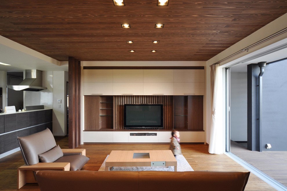 Идея дизайна: открытая гостиная комната в стиле модернизм с белыми стенами, паркетным полом среднего тона, телевизором на стене и коричневым полом