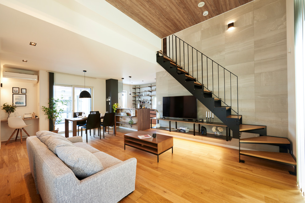Foto de salón abierto moderno de tamaño medio sin chimenea con paredes grises, suelo de madera clara, televisor independiente y suelo beige