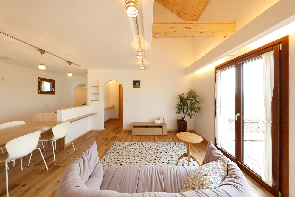 Esempio di un soggiorno mediterraneo aperto con pareti bianche, pavimento in legno massello medio, nessun camino, pavimento marrone, sala formale e TV autoportante