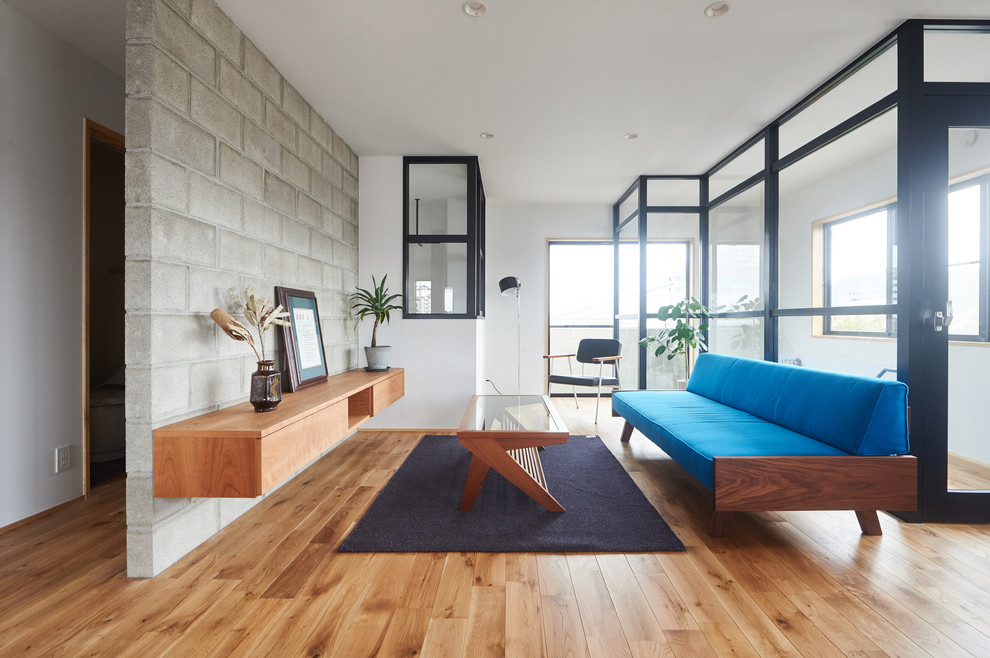 Ispirazione per un soggiorno design con pareti bianche, pavimento in legno massello medio e pavimento marrone