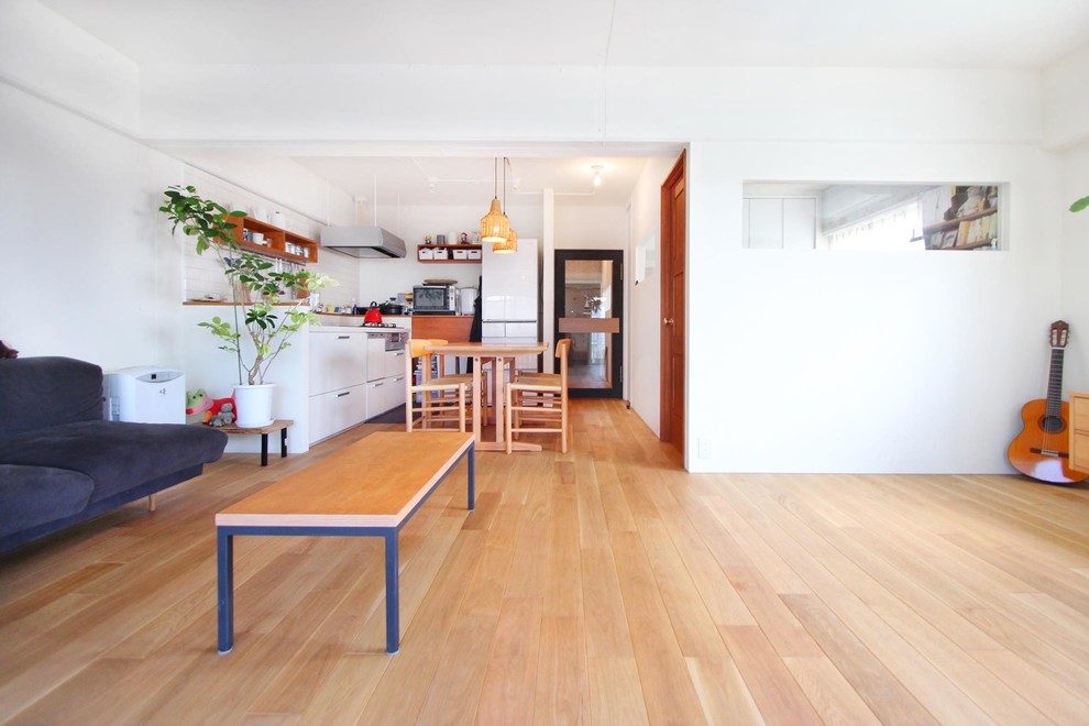 Ejemplo de salón abierto de estilo zen con paredes blancas, suelo de madera clara y suelo marrón