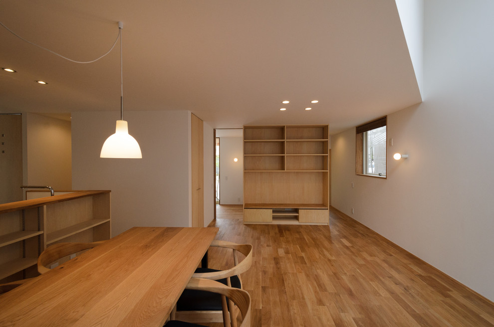 Exemple d'un salon scandinave ouvert avec un mur blanc, un sol en bois brun et aucune cheminée.