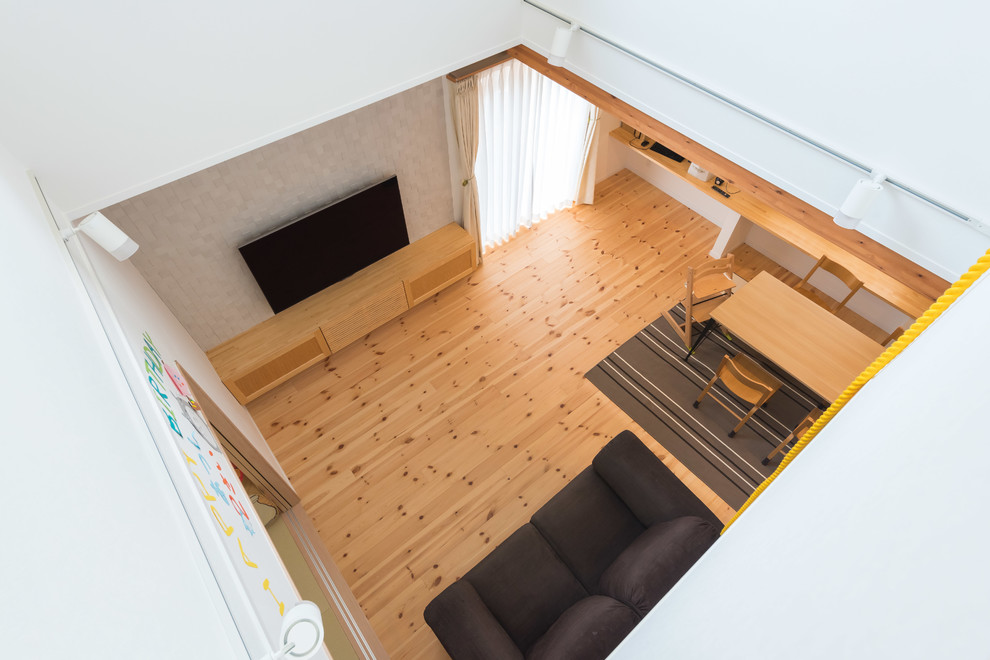 Inspiration för ett skandinaviskt allrum med öppen planlösning, med ett bibliotek, vita väggar, ljust trägolv och en väggmonterad TV