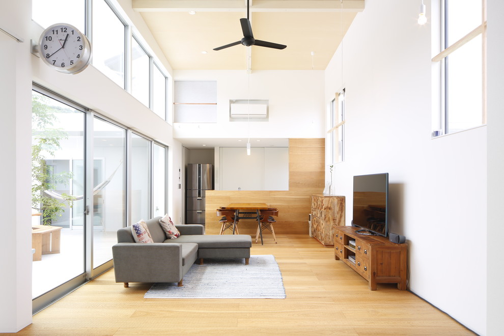 Ejemplo de salón contemporáneo con paredes blancas, suelo de madera clara y televisor independiente