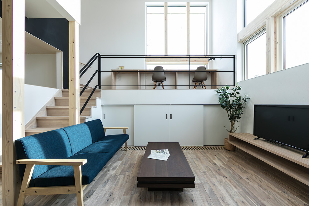 Свежая идея для дизайна: гостиная комната в стиле модернизм с белыми стенами, деревянным полом, отдельно стоящим телевизором и коричневым полом - отличное фото интерьера