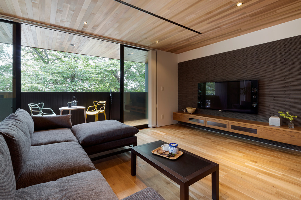 Réalisation d'un salon design ouvert avec un mur multicolore, un sol en bois brun, un téléviseur fixé au mur et un sol marron.
