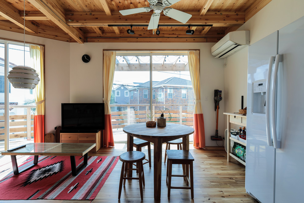 Modernes Wohnzimmer mit weißer Wandfarbe, gebeiztem Holzboden, freistehendem TV und braunem Boden in Sonstige