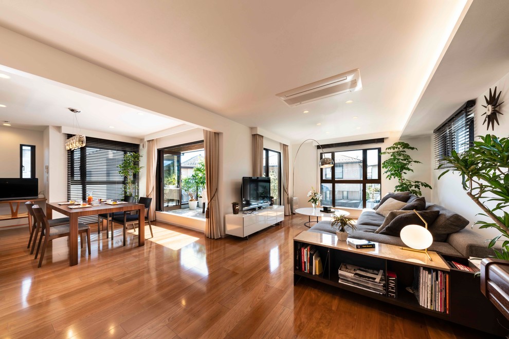 Cette photo montre un grand salon tendance ouvert avec un mur blanc, un sol en bois brun, un téléviseur indépendant et un sol marron.