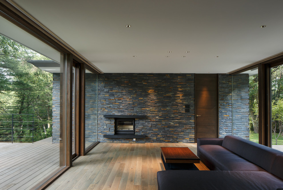 Стильный дизайн: гостиная комната в стиле модернизм с серыми стенами, светлым паркетным полом и стандартным камином - последний тренд
