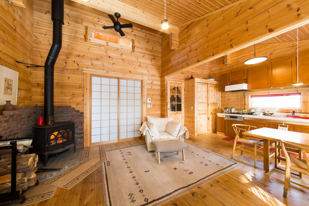 Idee per un soggiorno country con pareti marroni, pavimento in legno massello medio, stufa a legna, cornice del camino in mattoni e pavimento marrone