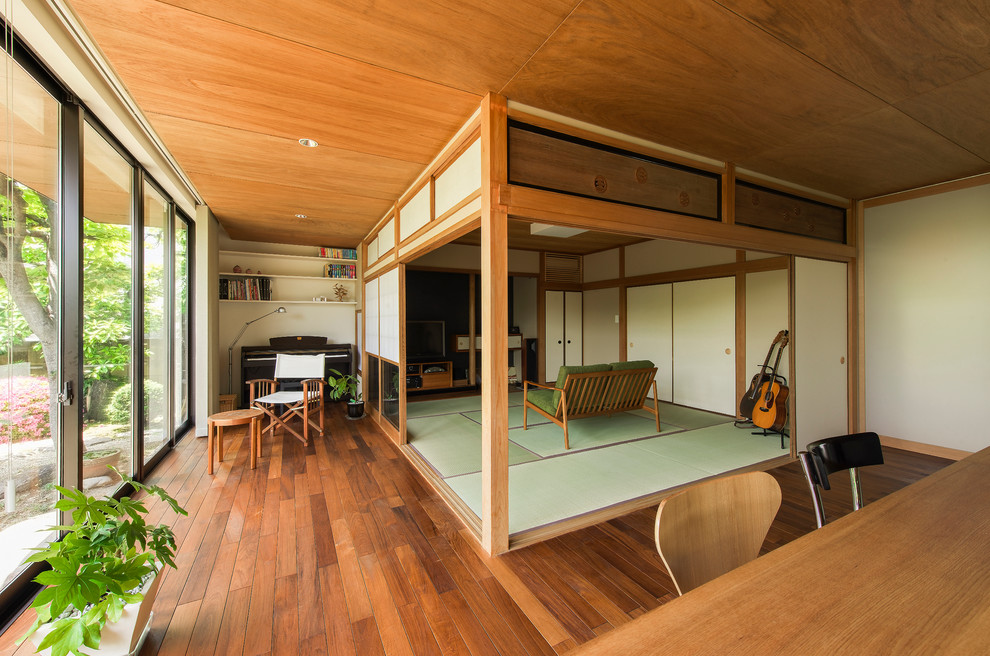 Источник вдохновения для домашнего уюта: открытая гостиная комната в восточном стиле с белыми стенами, паркетным полом среднего тона, музыкальной комнатой и зеленым полом