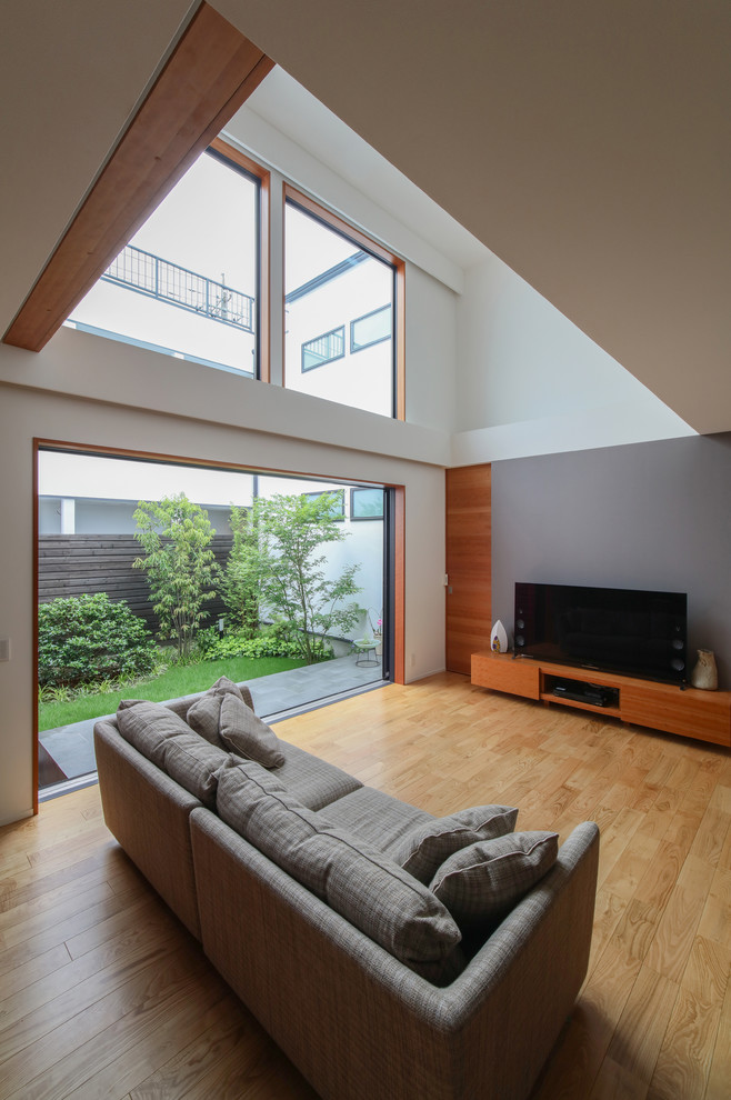 Foto di un soggiorno etnico con pareti grigie, pavimento in legno massello medio, TV autoportante e pavimento marrone