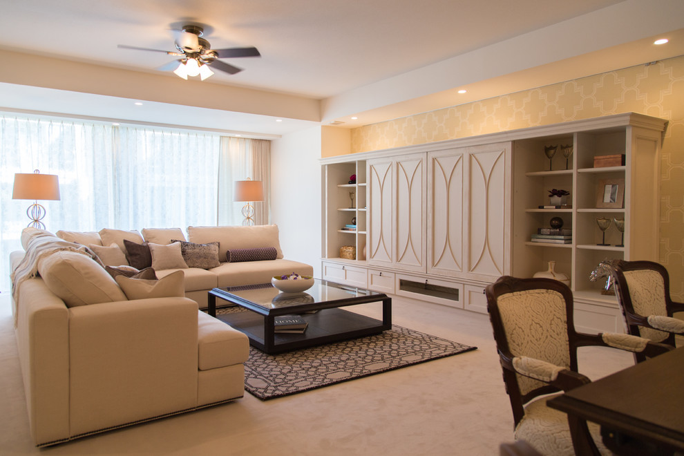 Cette image montre un salon design ouvert avec un mur beige, moquette, un téléviseur dissimulé et un sol beige.