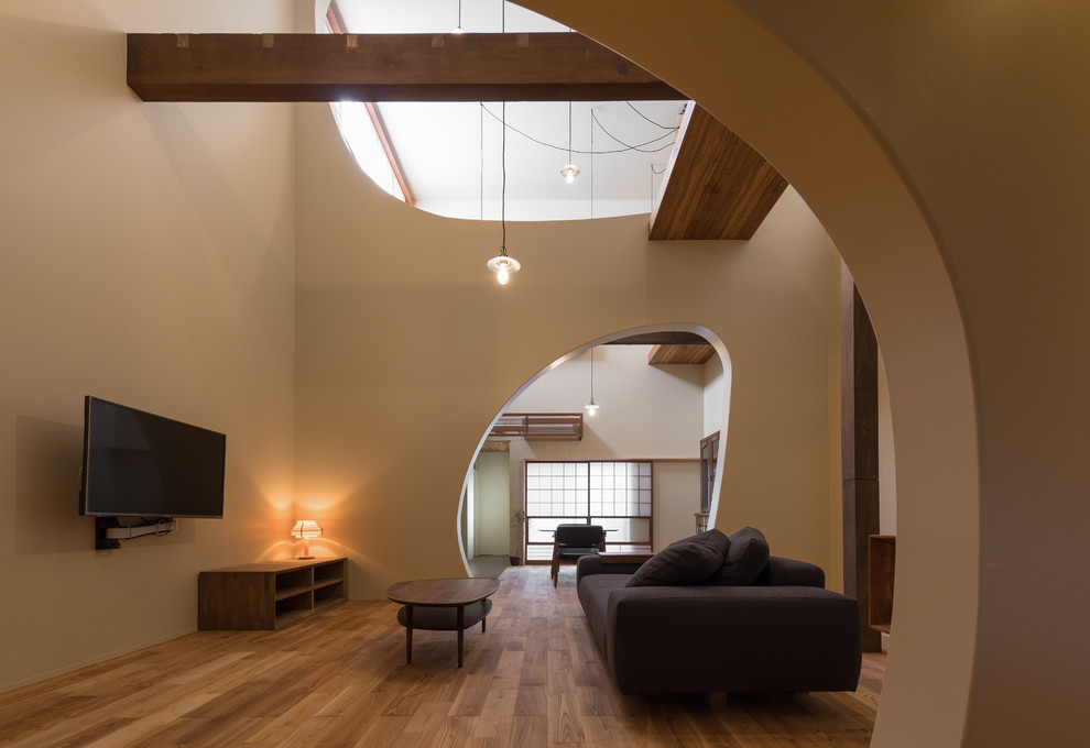 Immagine di un soggiorno minimalista di medie dimensioni e aperto con sala formale, pareti beige, pavimento in legno massello medio, TV a parete e pavimento marrone