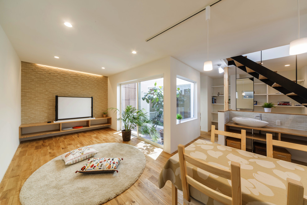 Offenes Asiatisches Wohnzimmer mit weißer Wandfarbe, hellem Holzboden, freistehendem TV und braunem Boden in Sonstige