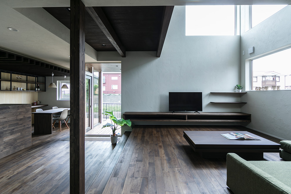 World-inspired living room in Sapporo with white walls, dark hardwood flooring, a freestanding tv and brown floors.