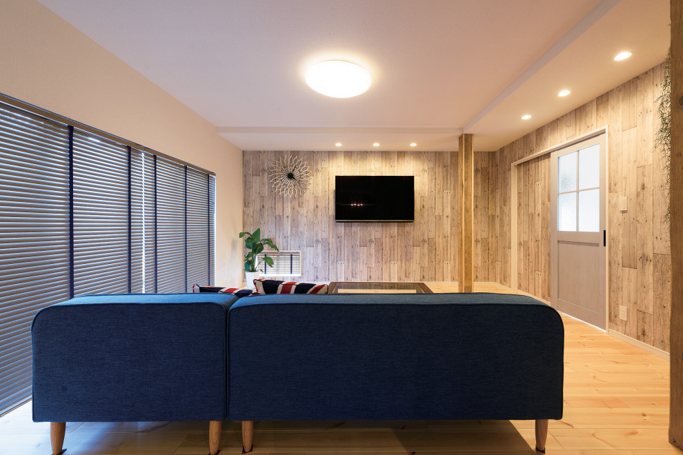 Ejemplo de salón para visitas abierto campestre con paredes blancas, suelo de madera clara, televisor colgado en la pared, papel pintado y madera