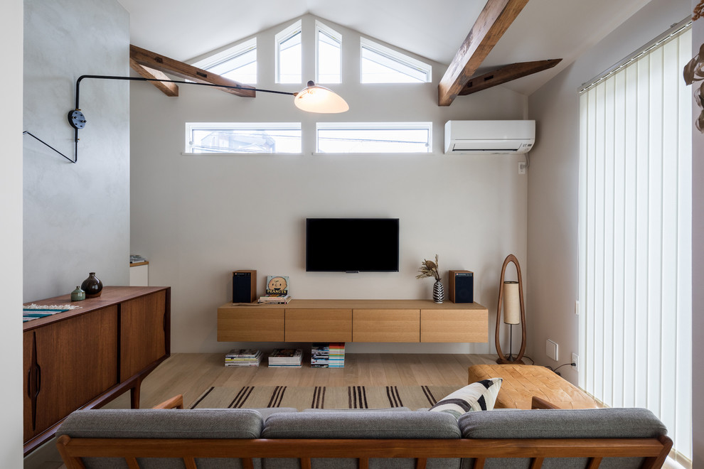 Exempel på ett modernt allrum med öppen planlösning, med vita väggar, målat trägolv, en väggmonterad TV och brunt golv
