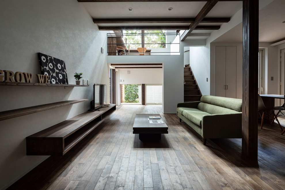 Immagine di un soggiorno moderno aperto con pareti bianche, parquet scuro, TV autoportante e pavimento marrone