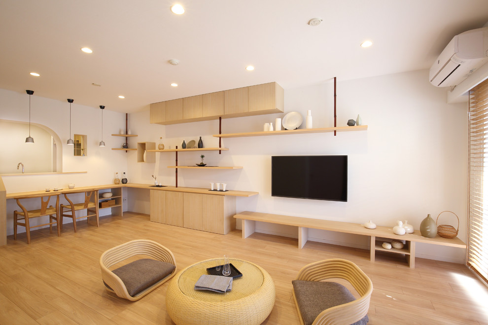 На фото: гостиная комната в восточном стиле с белыми стенами, светлым паркетным полом и телевизором на стене