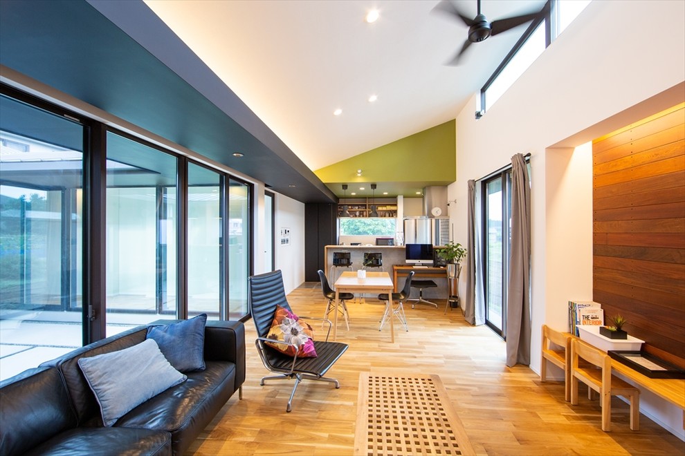 Immagine di un soggiorno minimalista di medie dimensioni e aperto con pareti verdi, pavimento in legno massello medio, TV a parete e pavimento marrone