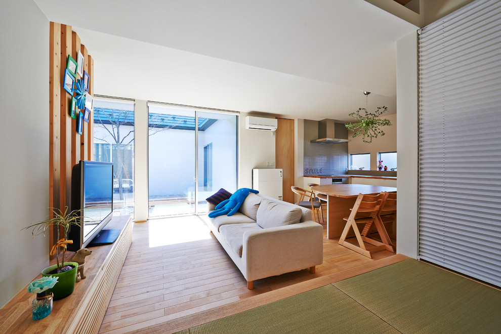 Источник вдохновения для домашнего уюта: открытая гостиная комната в восточном стиле с белыми стенами и отдельно стоящим телевизором