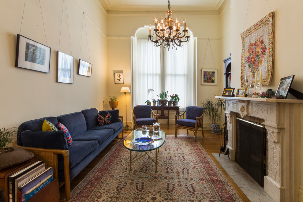 Fernseherloses Klassisches Wohnzimmer mit weißer Wandfarbe, braunem Holzboden, Kamin und Kaminumrandung aus Stein in Sonstige