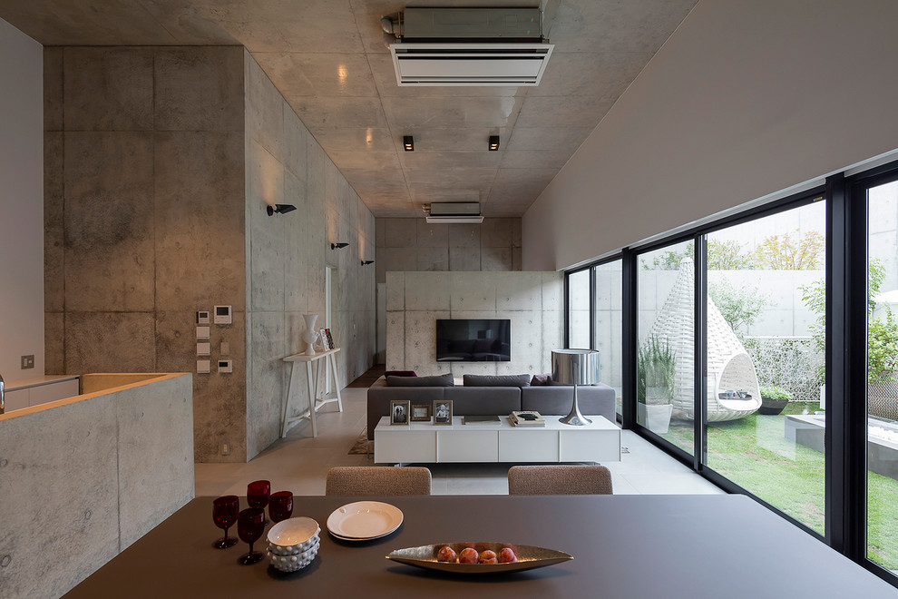 Стильный дизайн: гостиная комната в стиле модернизм с серыми стенами и телевизором на стене - последний тренд