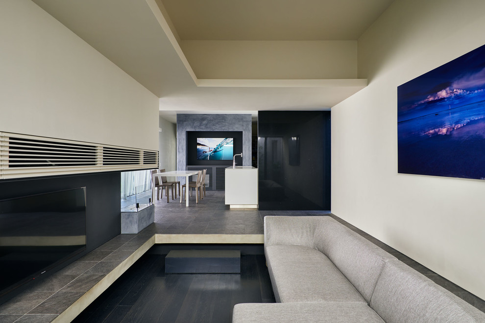 Modernes Wohnzimmer mit weißer Wandfarbe, gebeiztem Holzboden, TV-Wand und schwarzem Boden in Sonstige