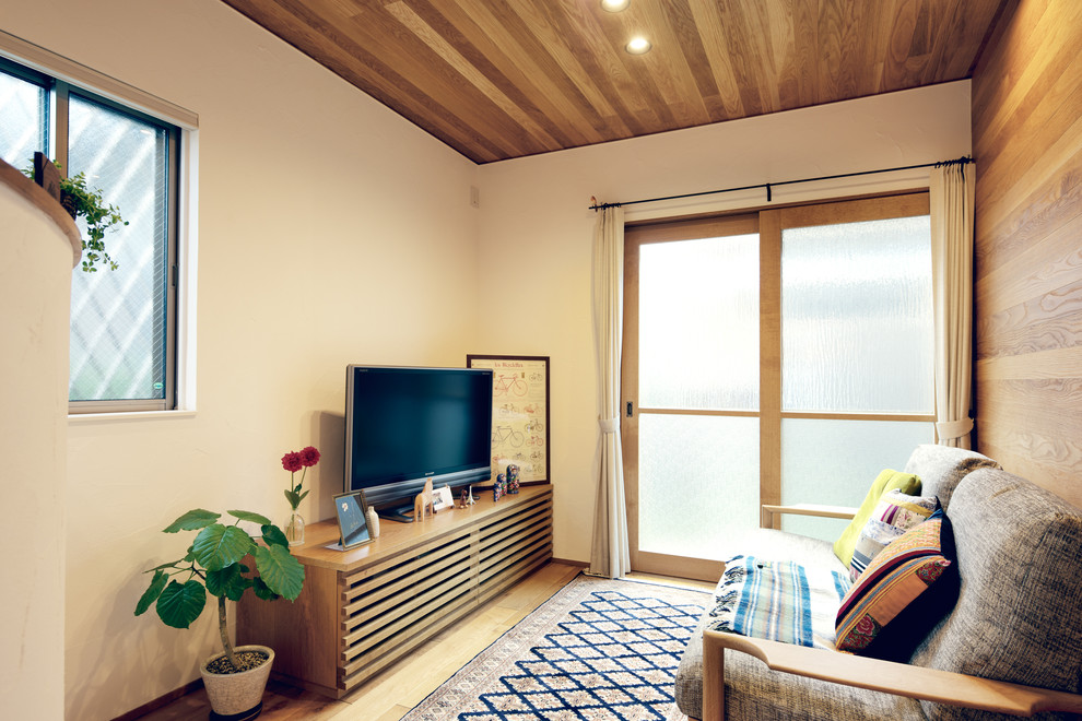 This is an example of a small scandinavian living room in Nagoya with multi-coloured walls, a freestanding tv, light hardwood flooring and brown floors.
