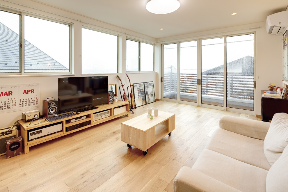 Diseño de salón abierto contemporáneo con paredes blancas, suelo de madera clara, televisor independiente y suelo beige