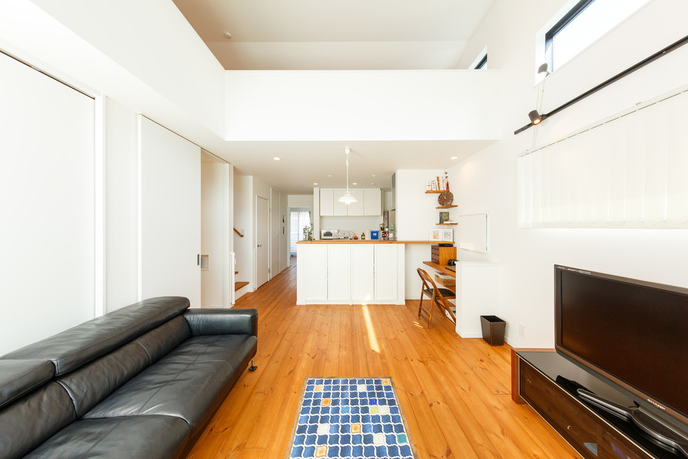Réalisation d'un salon minimaliste ouvert avec un mur blanc, un sol en bois brun, un téléviseur indépendant et un sol marron.