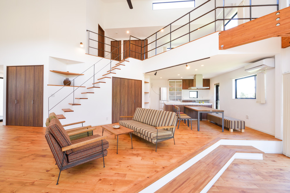 Immagine di un soggiorno etnico aperto con pareti bianche e pavimento in legno massello medio